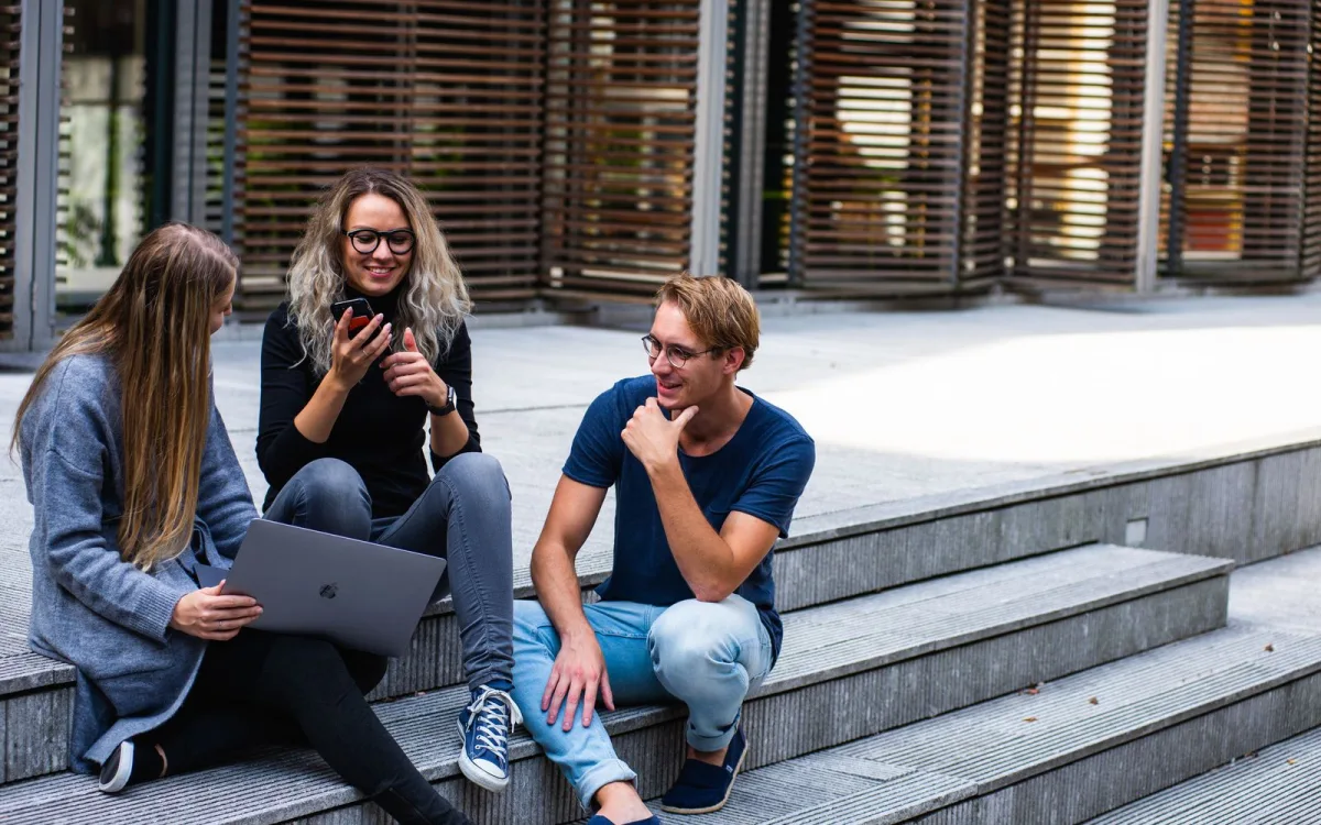 Studenter med laptop och mobil på campus, ett typiskt scenario för VPN i skolan, på universitet och på delade nätverk