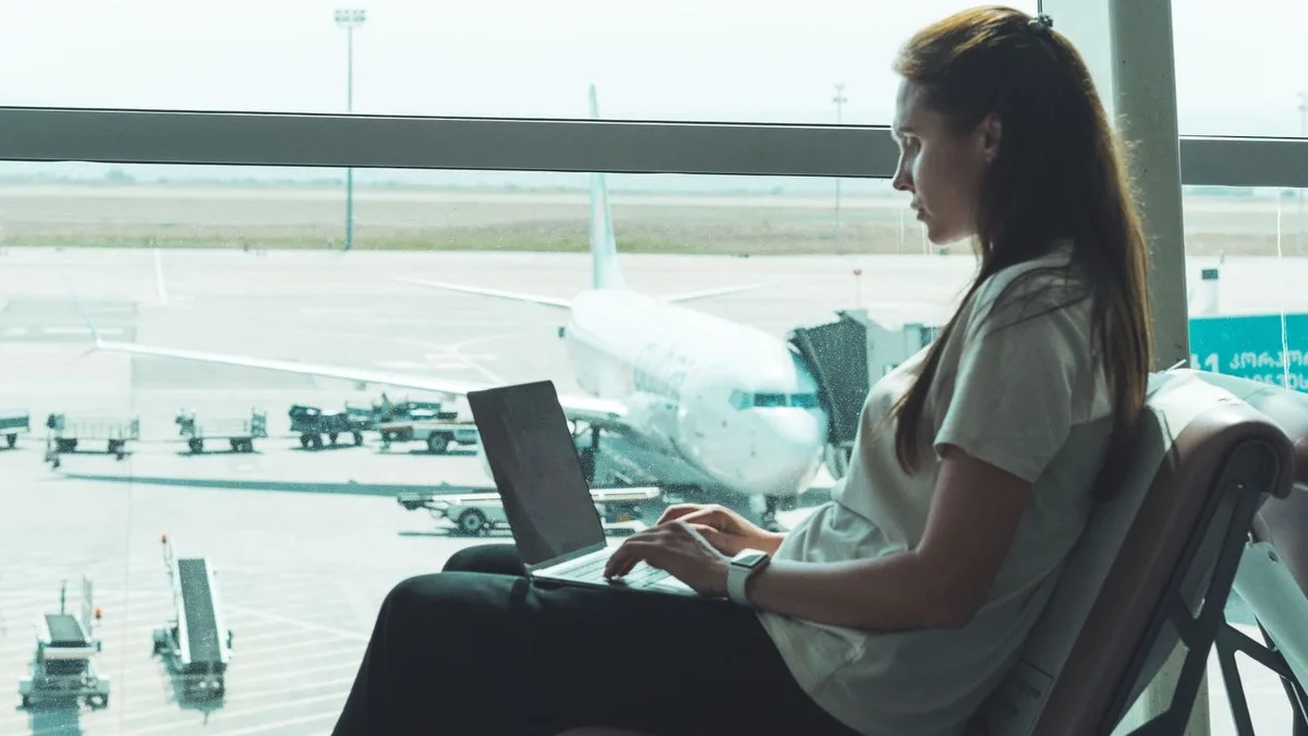 Person med laptop på flygplats som illustrerar VPN utomlands, resor och säker uppkoppling